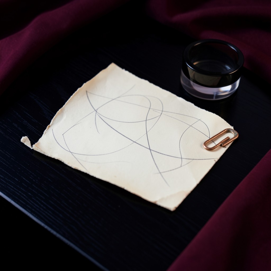 A sparse printed chart with a broken pencil curve beside a copper clip